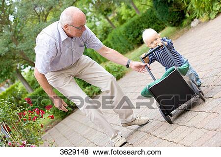 Grandfather and toddler with doll's pram outdoors View Large Photo Image Stock Photo - Grandfather and toddler with doll's pram outdoors . Fotosearch