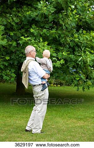 Grandfather carrying toddler outdoors View Large Photo Image Stock Photo - Grandfather carrying toddler outdoors . Fotosearch