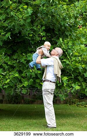 Stock Photo - Grandfather carrying toddler outdoors . Fotosearch