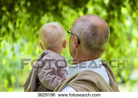 Stock Photograph - Grandfather carrying toddler outdoors, rear view . Fotosearch