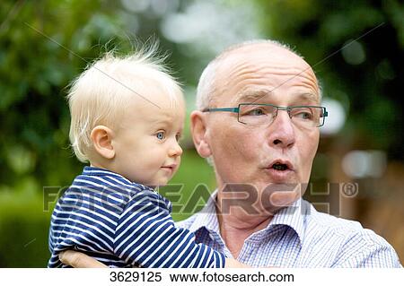 Stock Photography - Grandfather carrying toddler outdoors, portrait . Fotosearch