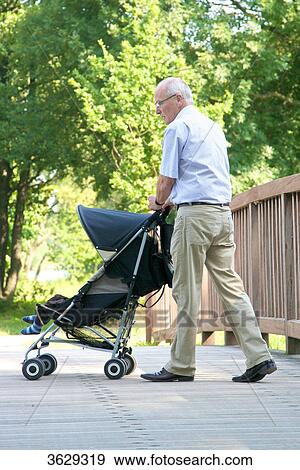 Grandfather going for a walk with grandson in pushchair View Large Photo Image Stock Photo - Grandfather going for a walk with grandson in pushchair . Fotosearch