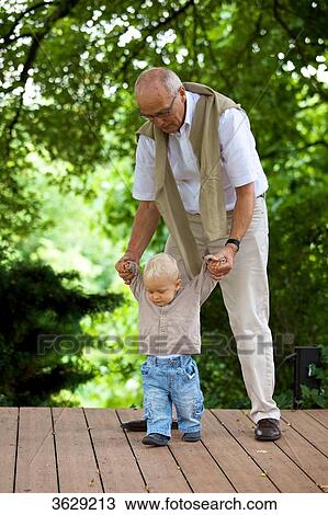 Grandfather helping toddler to walk View Large Photo Image Stock Image - Grandfather helping toddler to walk . Fotosearch