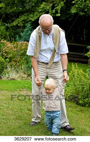 Stock Photo - Grandfather helping toddler to walk . Fotosearch