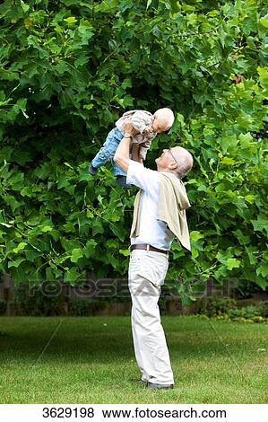 Grandfather lifting toddler outdoors View Large Photo Image Stock Photo - Grandfather lifting toddler outdoors . Fotosearch