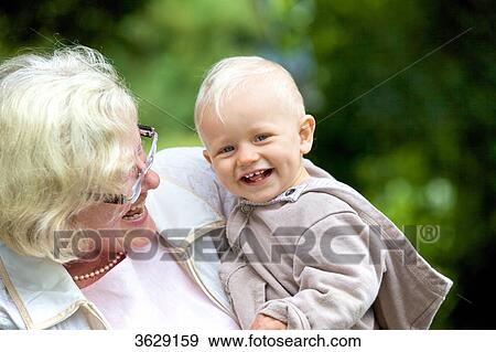 Stock Photo - Grandmother carrying toddler outdoors, portrait . Fotosearch