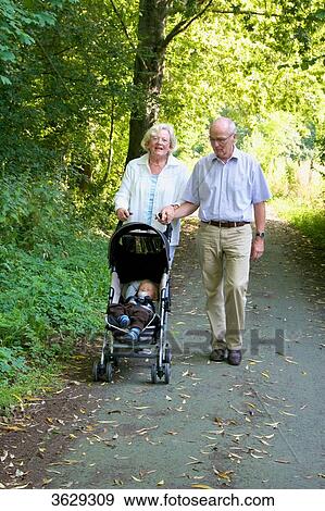 Stock Photo - Grandparents going for a walk with grandson in pushchair . Fotosearch