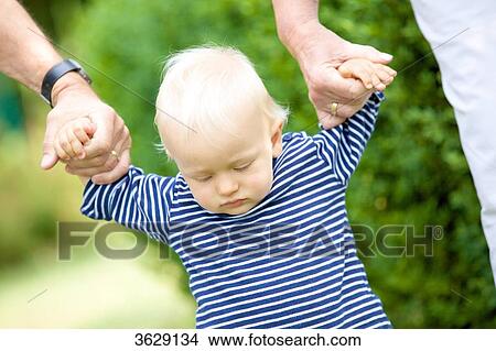 Grandparents walking hand in hand with toddler View Large Photo Image Picture - Grandparents walking hand in hand with toddler . Fotosearch