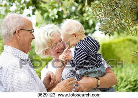 Stock Image - Grandparents with toddler in garden . Fotosearch
