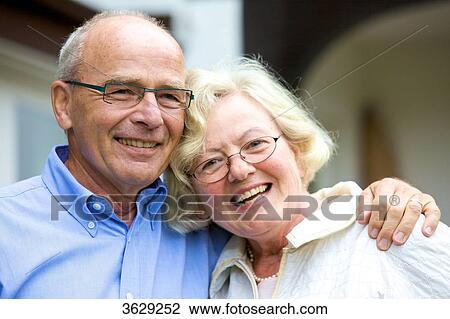 Happy senior couple embracing in front of residential building, portrait View Large Photo Image Stock Image - Happy senior couple embracing in front of residential building, portrait . Fotosearch