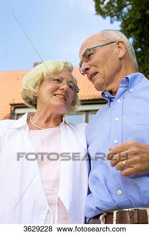 Stock Photo - Happy senior couple in front of residential building . Fotosearch
