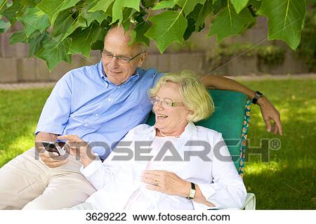 Happy senior couple with smartphone in garden View Large Photo Image Stock Image - Happy senior couple with smartphone in garden . Fotosearch