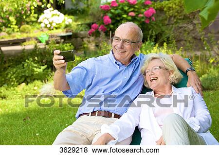 Happy senior couple with smartphone in garden View Large Photo Image Stock Photo - Happy senior couple with smartphone in garden . Fotosearch