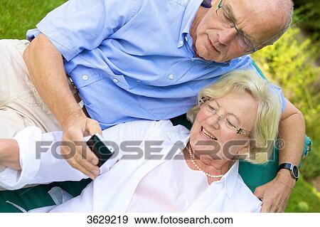 Stock Photo - Happy senior couple with smartphone in garden . Fotosearch