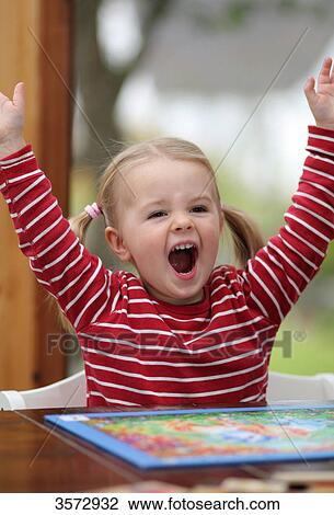 Stock Image - Laughing girl doing a jigsaw . Fotosearch