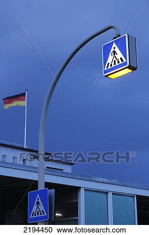 Stock Image - Low angle view of pedestrian crossing sign lit up at dusk, Hamburg, Germany . Fotosearch