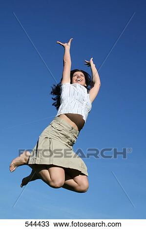 Low angle view of young woman jumping in mid-air View Large Photo Image Stock Image - Low angle view of young woman jumping in mid-air . Fotosearch
