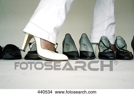 Picture - Low section view of person crossing row of shoes . Fotosearch