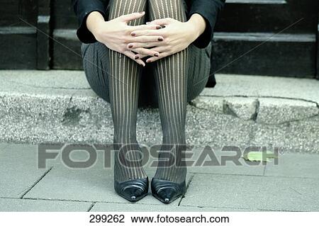 Stock Image - Low section view of woman hugging her knees . Fotosearch
