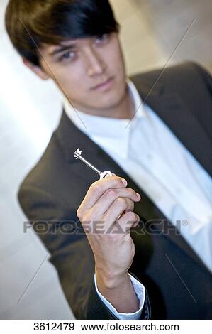 Stock Photo - Man holding key for safe deposit box . Fotosearch