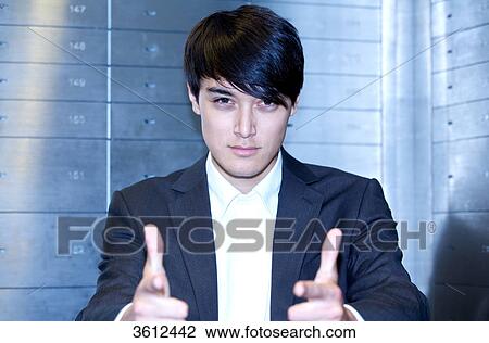 Stock Image - Man in front of safe deposit boxes, portrait . Fotosearch