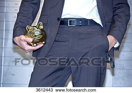 Stock Image - Man in front of safe deposit boxes holding golden piggy bank, close-up . Fotosearch