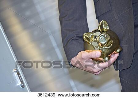 Man in front of safe deposit boxes holding golden piggy bank, close-up View Large Photo Image Stock Photo - Man in front of safe deposit boxes holding golden piggy bank, close-up . Fotosearch
