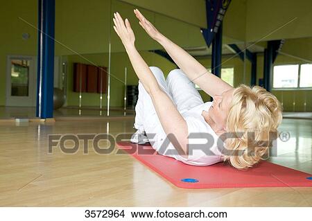 Mature woman exercising on gymnastics mat in gym View Large Photo Image Picture - Mature woman exercising on gymnastics mat in gym . Fotosearch