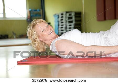 Stock Photo - Mature woman exercising on gymnastics mat in gym . Fotosearch
