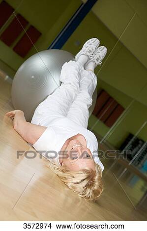 Mature woman exercising with fitness ball in gym View Large Photo Image Picture - Mature woman exercising with fitness ball in gym . Fotosearch