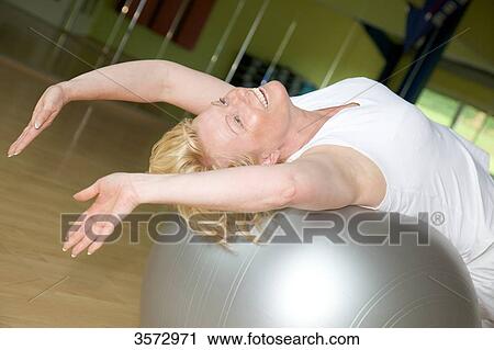 Mature woman exercising with fitness ball in gym View Large Photo Image Stock Image - Mature woman exercising with fitness ball in gym . Fotosearch