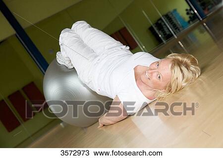 Mature woman exercising with fitness ball in gym View Large Photo Image Stock Image - Mature woman exercising with fitness ball in gym . Fotosearch