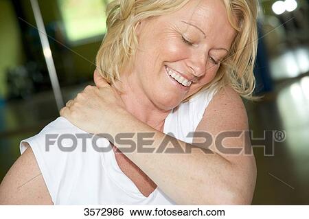 Mature woman touching her shoulder View Large Photo Image Stock Photograph - Mature woman touching her shoulder . Fotosearch