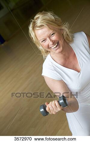 Mature woman weight lifting in gym View Large Photo Image Stock Image - Mature woman weight lifting in gym . Fotosearch