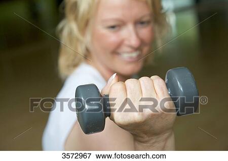 Stock Photo - Mature woman weight lifting in gym . Fotosearch
