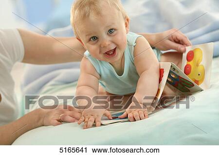 Stock Image - Mother and baby with picture book . Fotosearch