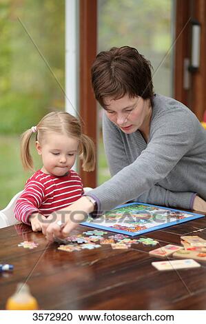 Stock Image - Mother and daughte doing a jigsaw at table . Fotosearch