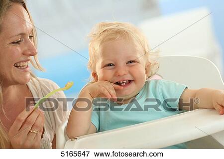 Mother feeding laughing baby View Large Photo Image Stock Photo - Mother feeding laughing baby . Fotosearch