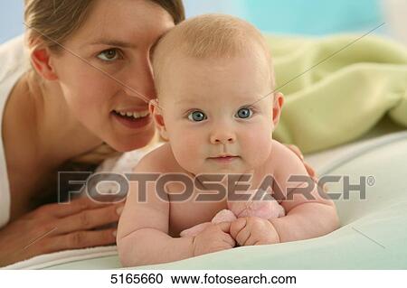Stock Image - Mother lying with baby on blanket . Fotosearch