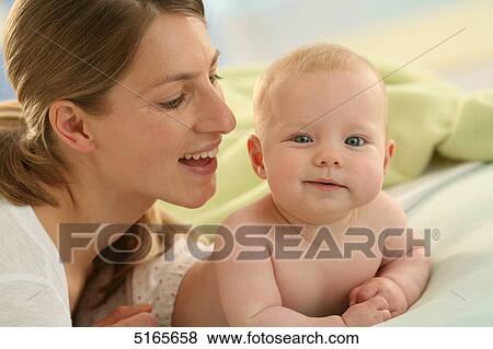 Stock Photo - Mother lying with baby on blanket . Fotosearch