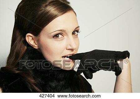 Picture - Portrait of young woman biting leather glove . Fotosearch