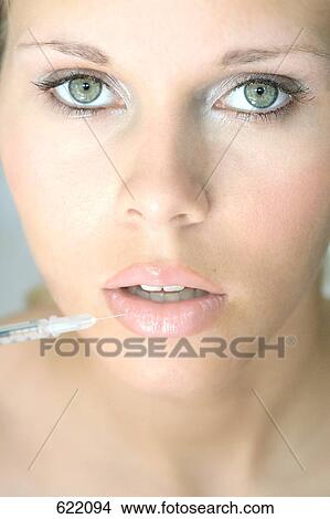 Picture - Portrait of young woman getting a shot in her lip . Fotosearch