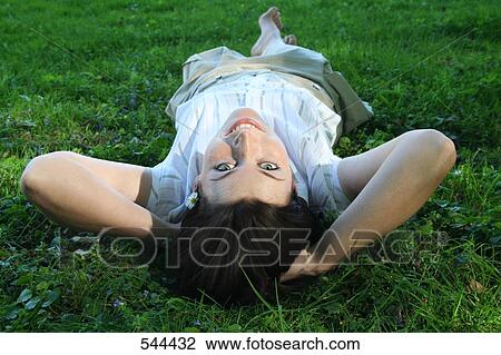 Portrait of young woman lying on grass View Large Photo Image Stock Image - Portrait of young woman lying on grass . Fotosearch