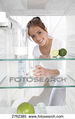 Portrait of young woman putting milkglass in refrigerator and smiling View Large Photo Image Stock Photography - Portrait of young woman putting milkglass in refrigerator and smiling . Fotosearch