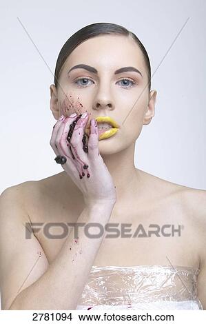 Picture - Portrait of young woman rubbing blueberries on her face . Fotosearch