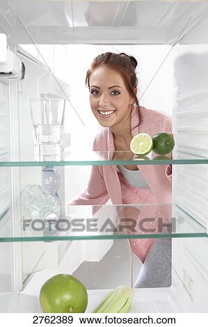 Portrait of young woman smiling in front of open refrigerator View Large Photo Image Stock Photo - Portrait of young woman smiling in front of open refrigerator . Fotosearch