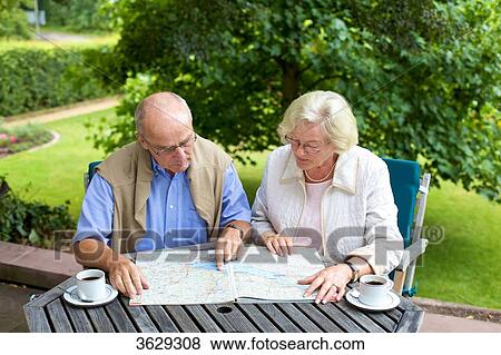 Stock Photo - Senior couple on terrace looking in road map . Fotosearch