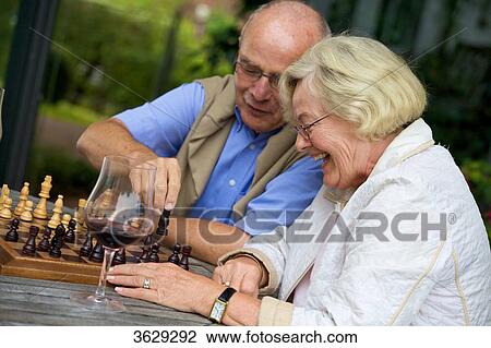 Stock Image - Senior couple on terrace playing chess . Fotosearch