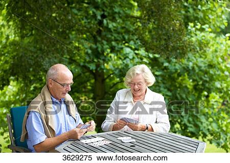 Stock Photography - Senior couple playing cards on the terrace . Fotosearch