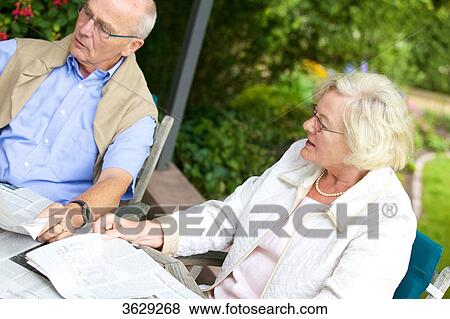 Senior couple reading newspaper on the terrace View Large Photo Image Stock Photo - Senior couple reading newspaper on the terrace . Fotosearch